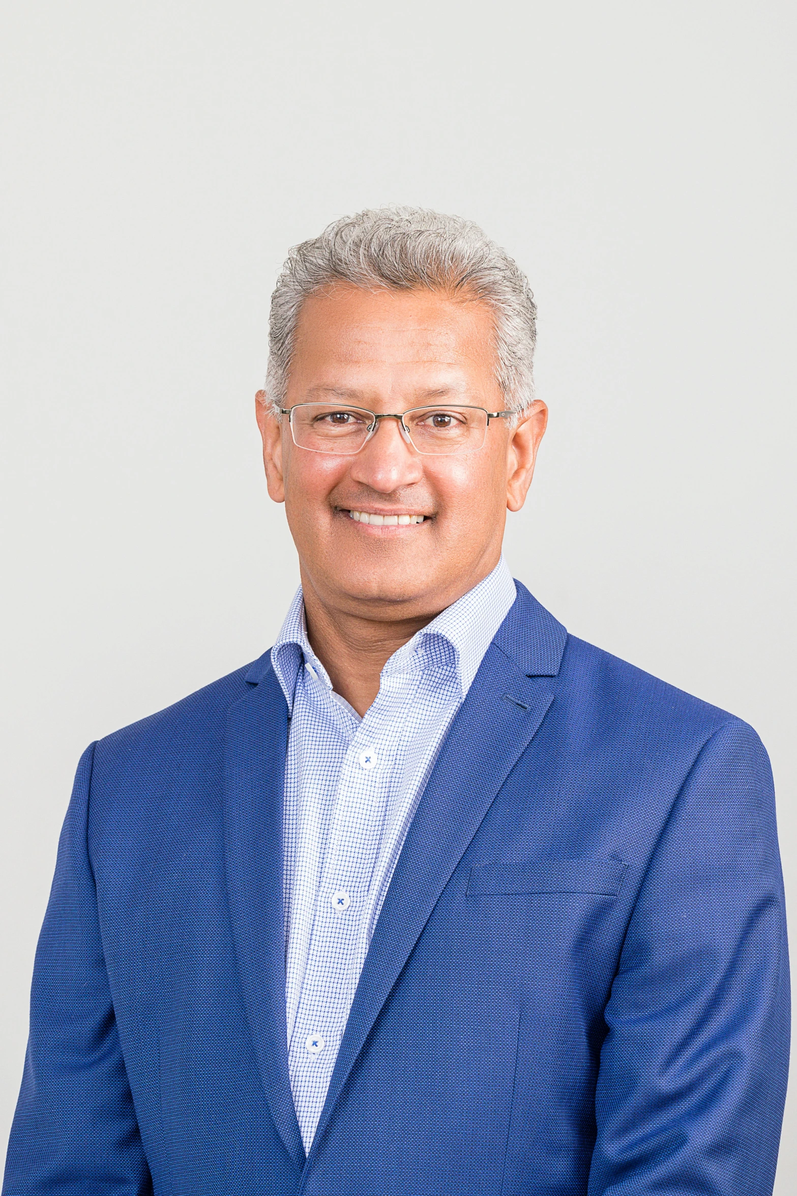 an indian man in a blue suit and glasses