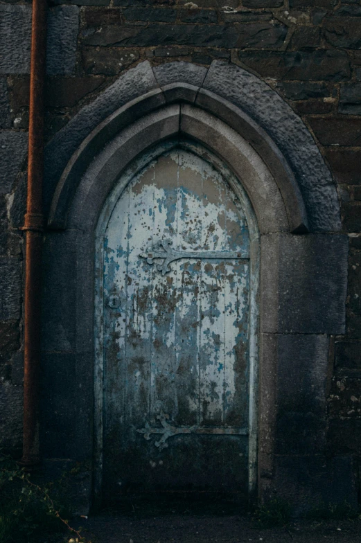 a dilapidated door with a faded design is in a stone building