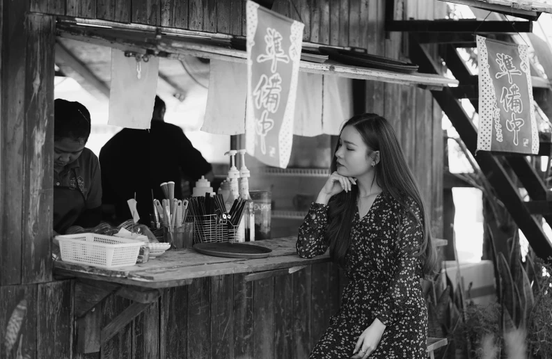 woman leaning against wall in small store near signs