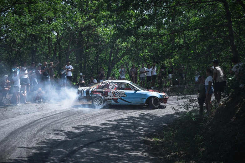 a group of people stand around the wrecked race car