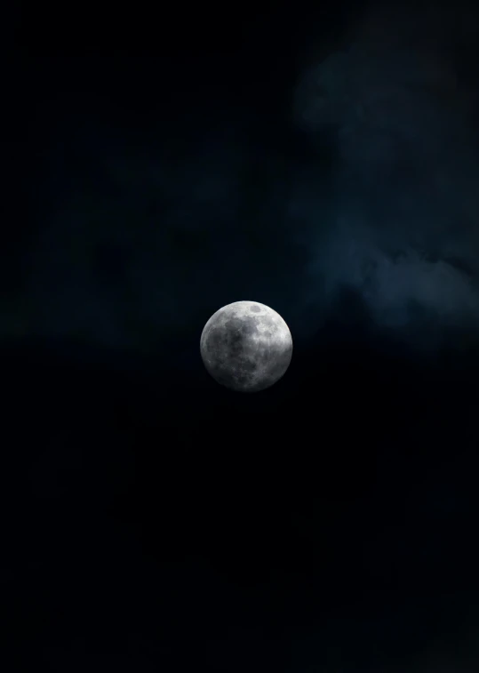 the moon is seen through dark clouds and it appears to be half full