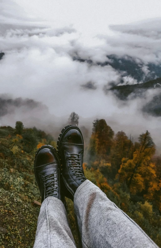 a person wearing sneakers on a hill above the clouds
