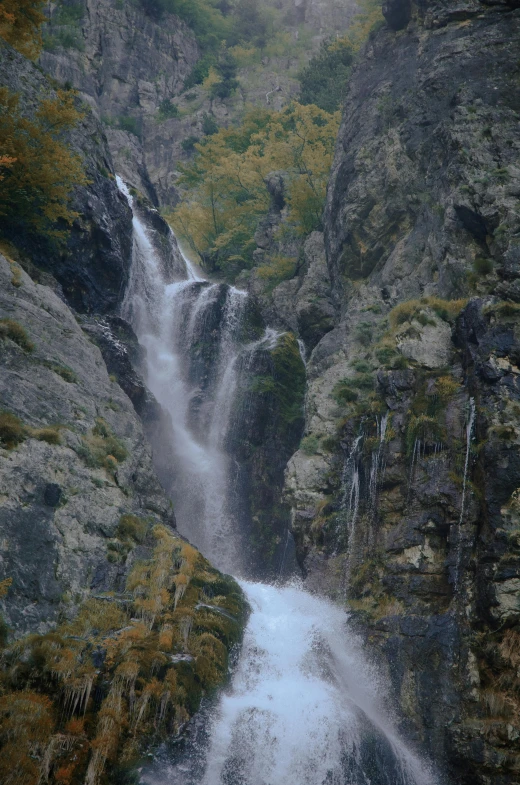 large waterfall surrounded by tall, mossy rocks