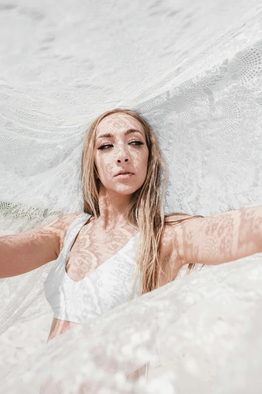 a beautiful woman laying down in white clothing