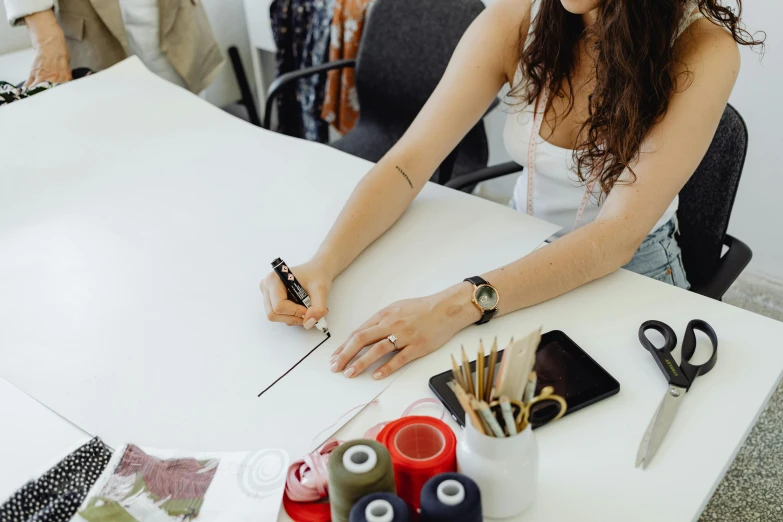 a woman that is sitting down at a table with some scissors