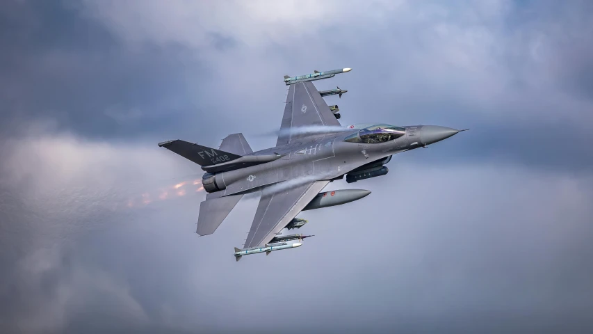 a fighter jet flying through a cloudy blue sky