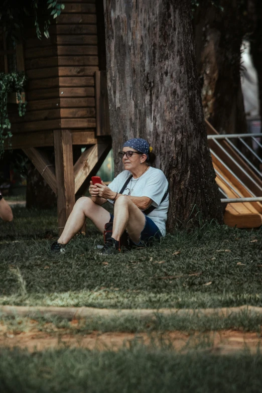 a man sitting under a tree on the grass