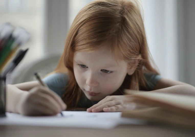 a small girl is using a pen to write