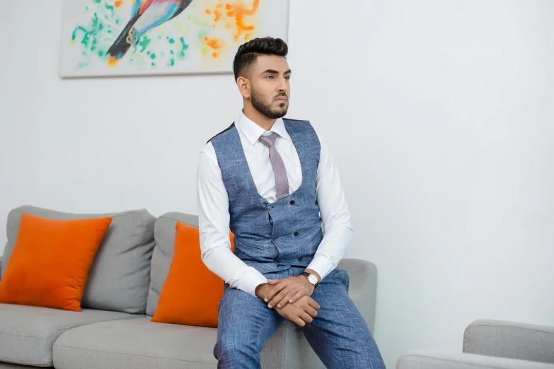 a man in an elegantly styled suit sits on the couch