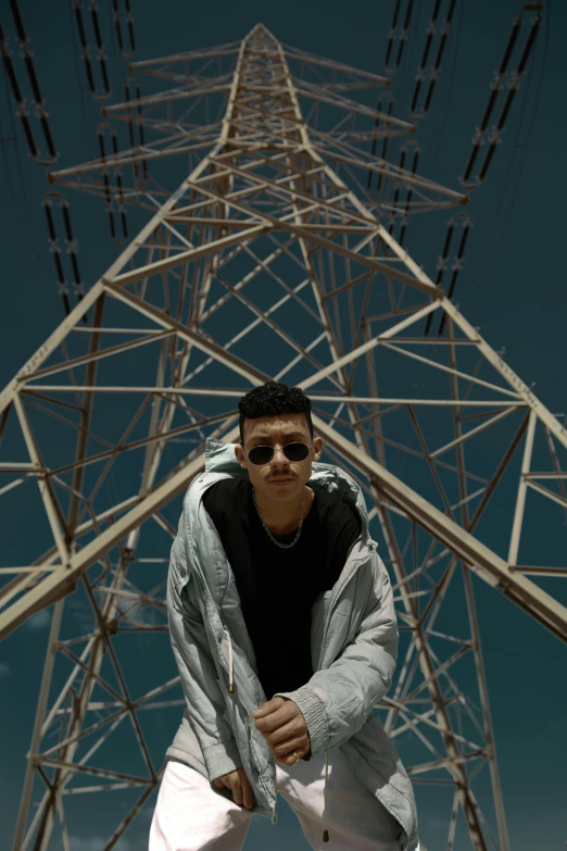 the person is standing under an electrical tower