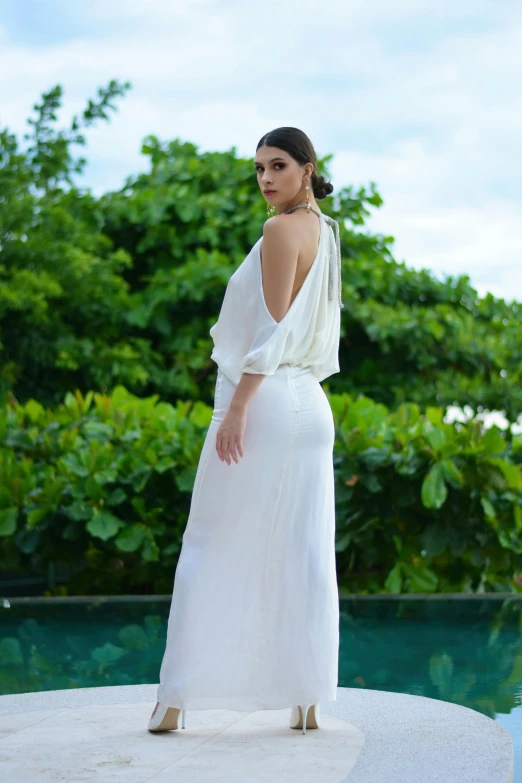 a woman in a white dress by a pool