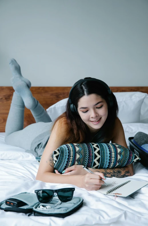 a girl laying on top of a bed with headphones