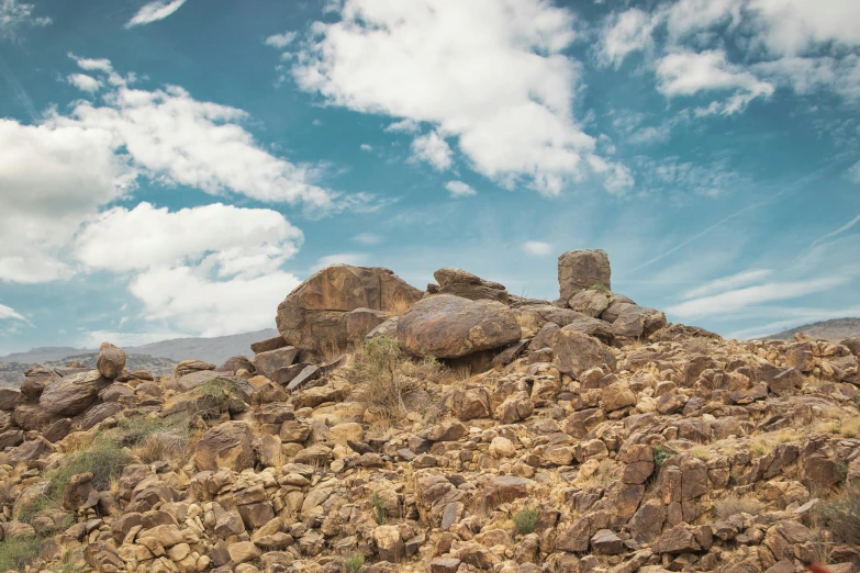 a hillside full of boulders on a cloudy day