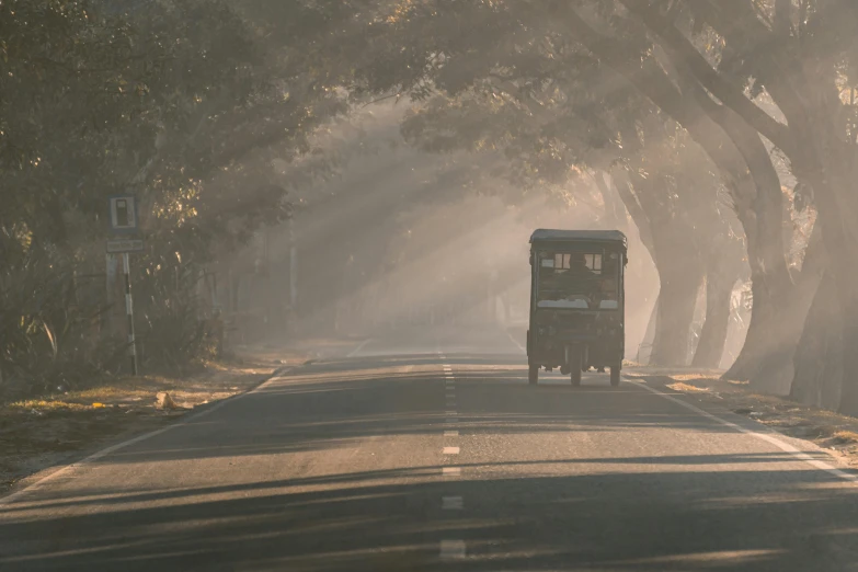 a truck going down a country road near many trees