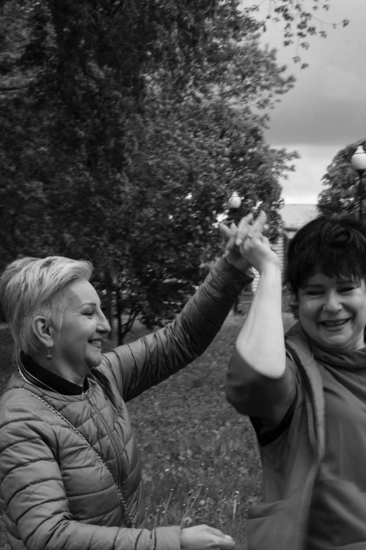 two women standing outside with their arms raised