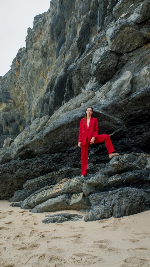 a person wearing red standing near a rock wall