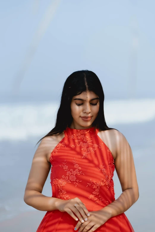 a woman is wearing an orange dress at the beach