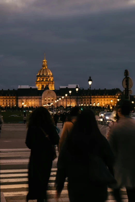 people cross at a crosswalk at dusk in a city