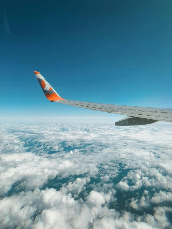 the wing of a plane is in the sky above clouds