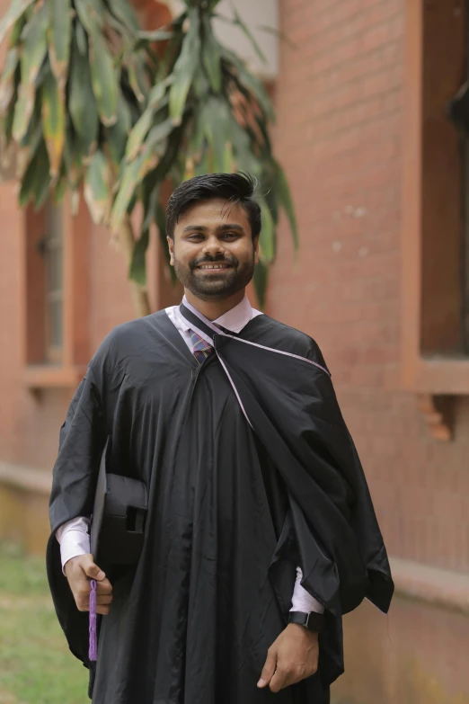 a man dressed in his graduation gown is standing outside