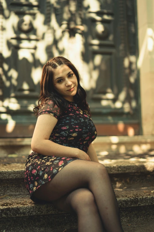 young woman in dress sits on stairs outside