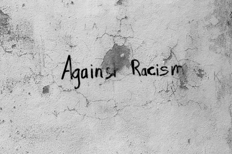 graffiti writing on a wall that says against racism