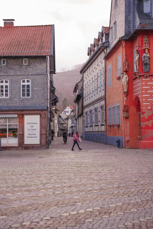 some people walking down a cobblestone road in an old town