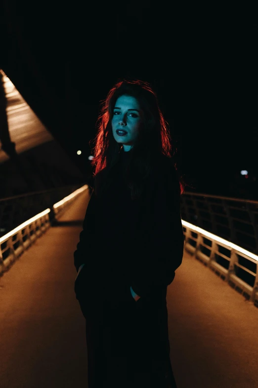 a woman standing on a bridge at night