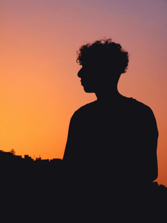 a man standing in front of an orange and purple sky