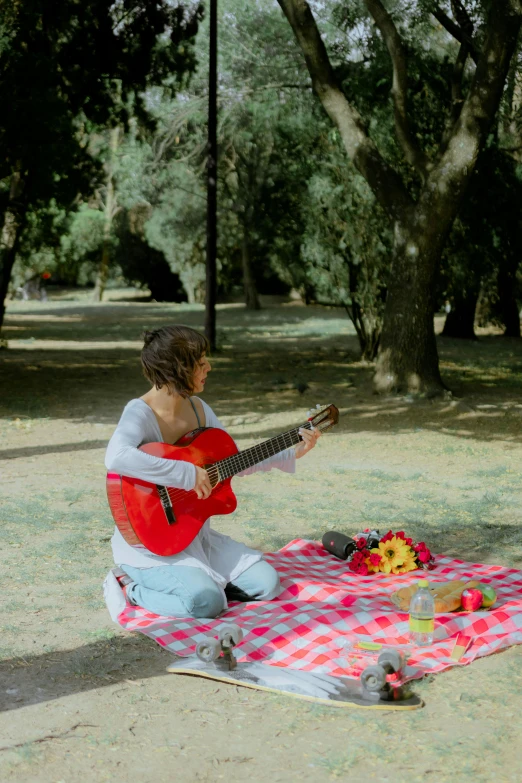 a young man playing a guitar in a park