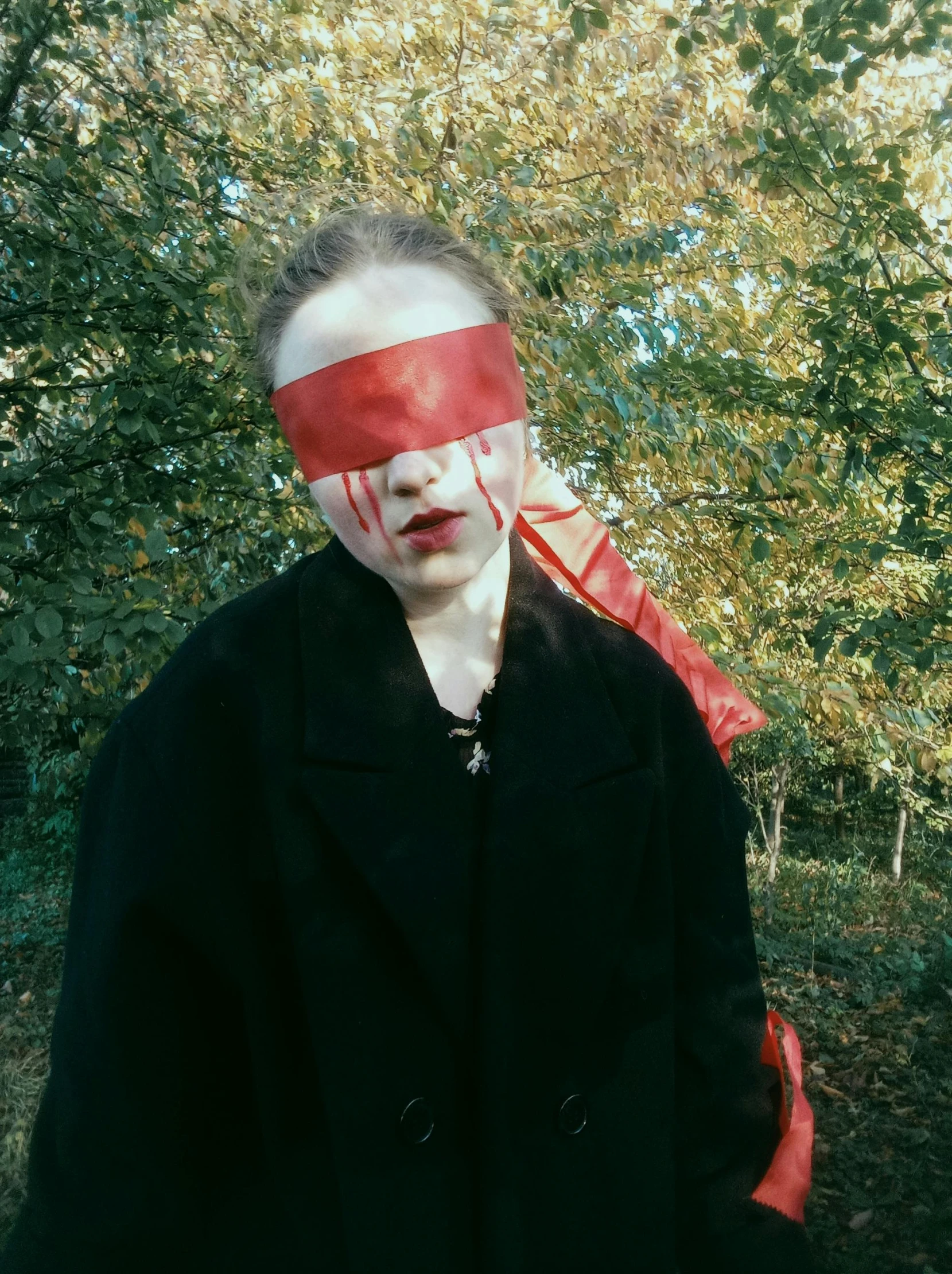 a man with tape on his face in front of trees