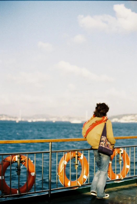 a woman is leaning against a railing overlooking the ocean