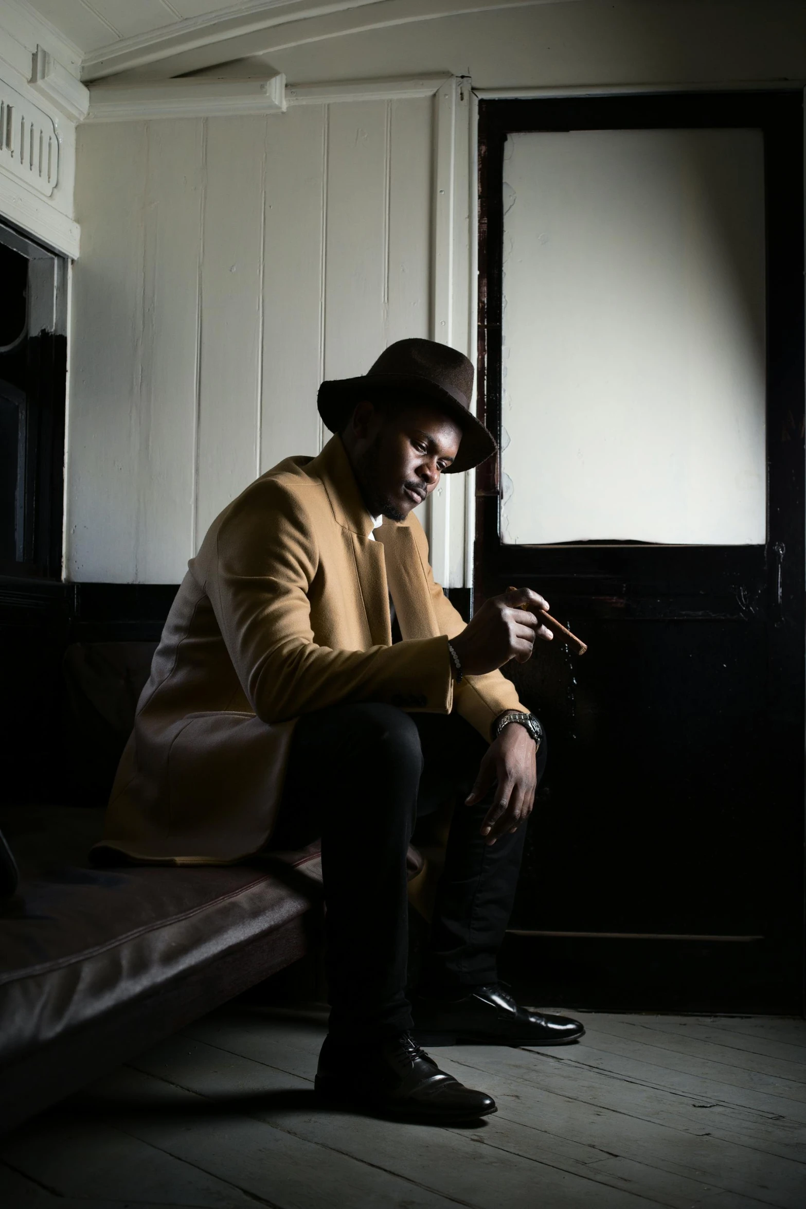 a man sitting next to a bed looking at his cell phone