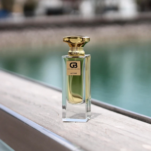 a perfume bottle with a gold top sitting on a wooden rail