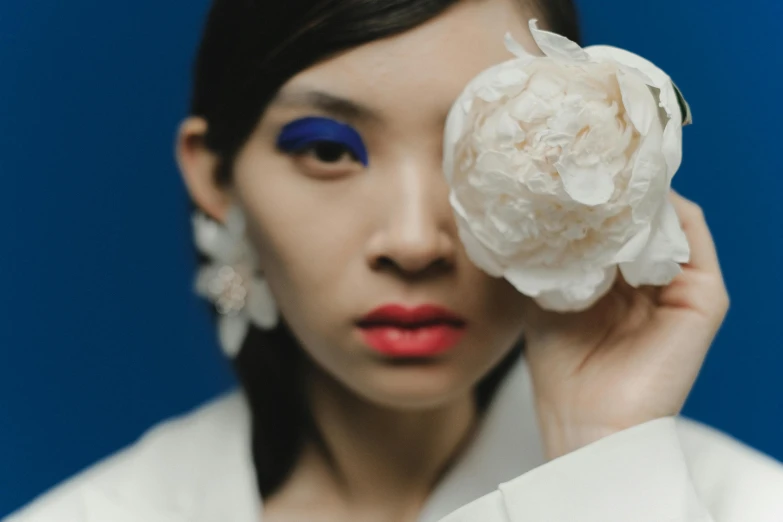 a young woman with black hair holding a flower