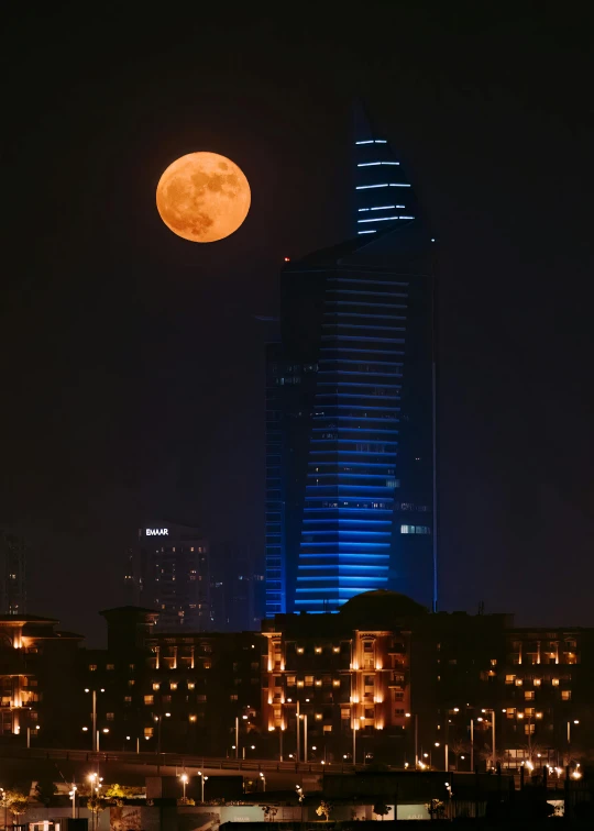 the moon sets over some city buildings at night