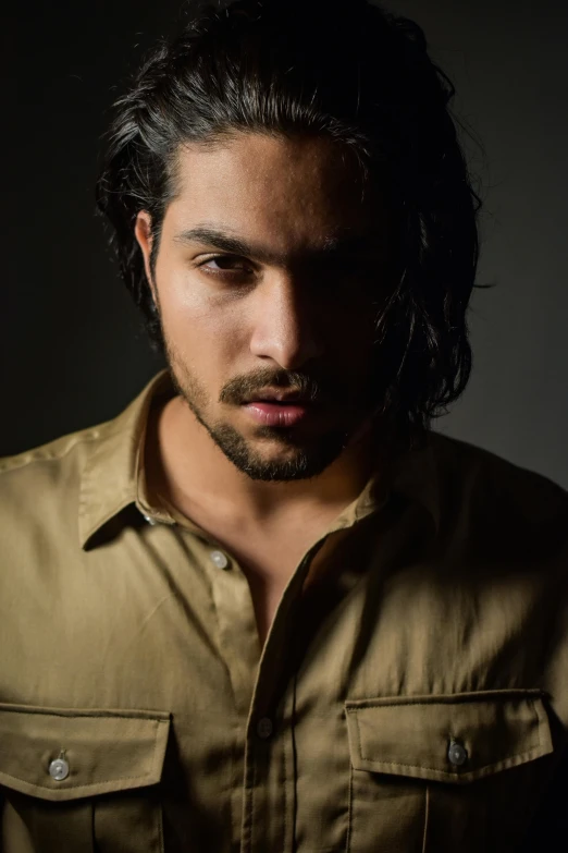 a man with long hair and a beard, wearing an brown shirt