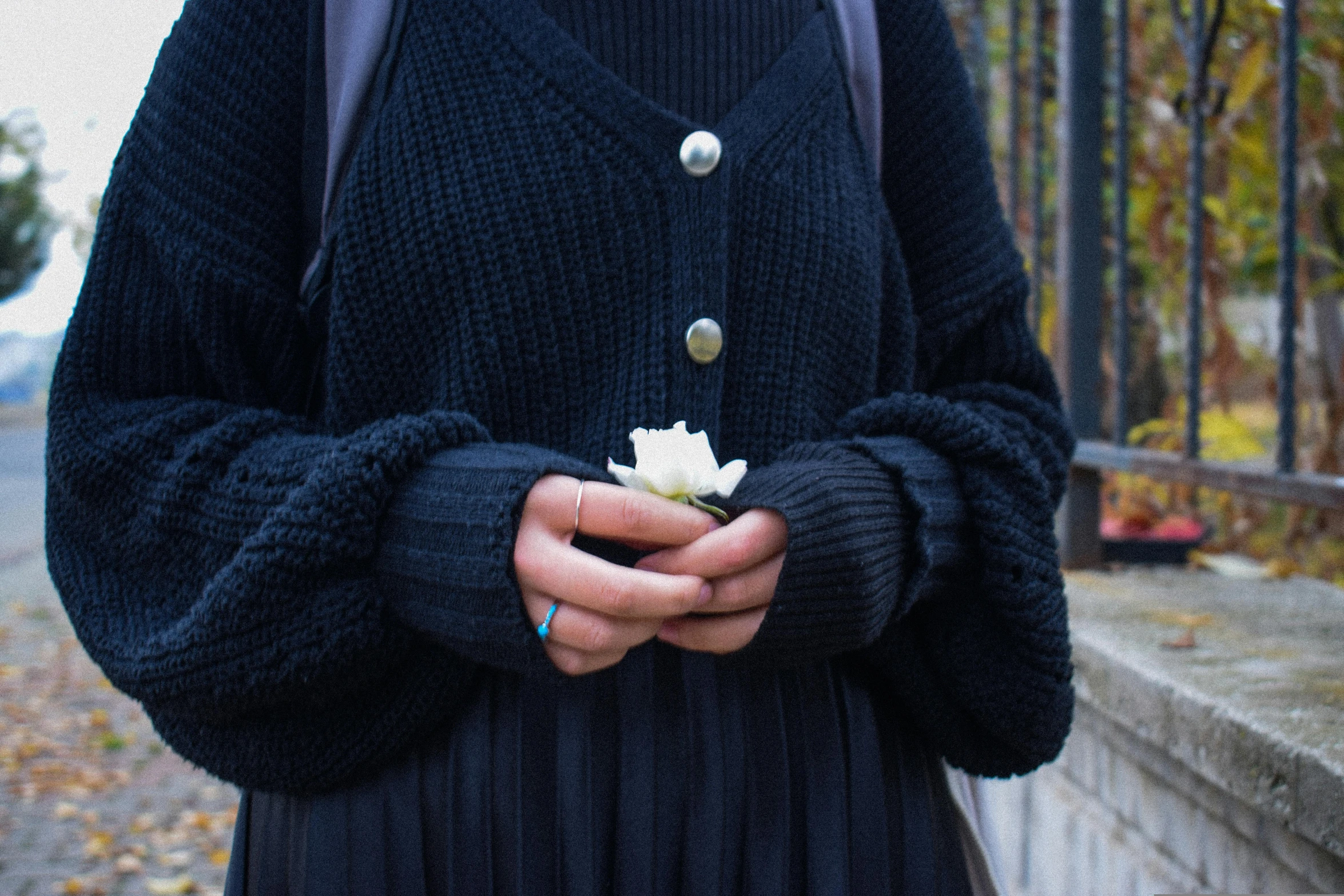 woman in blue jacket holding a flower and wearing black