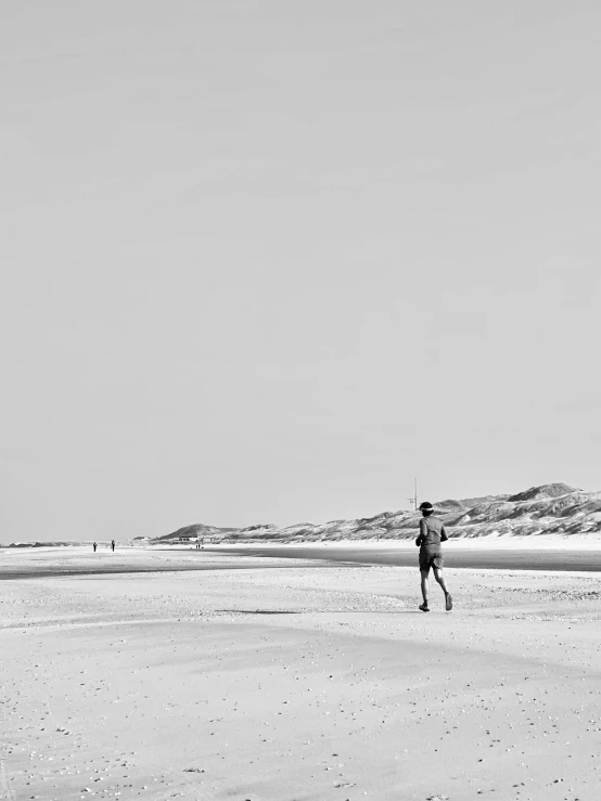 black and white image of people on beach flying a kite