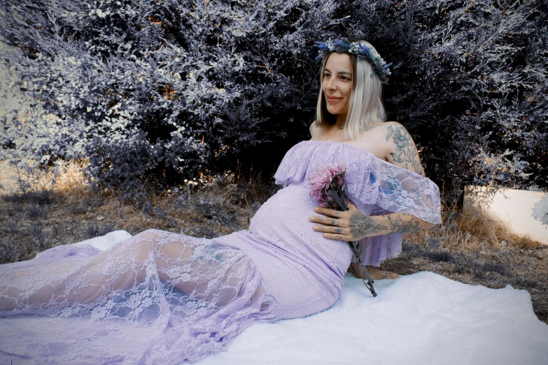 a woman sitting on the ground in a lavender gown