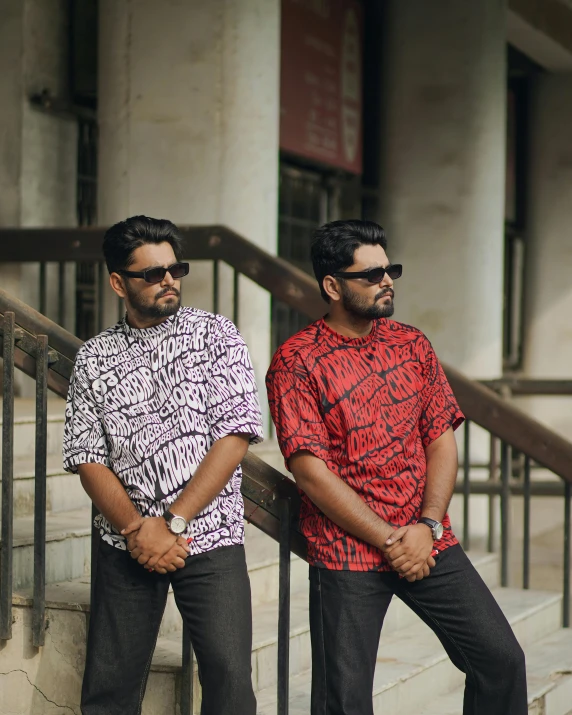 two men are standing with one another in front of the stairs