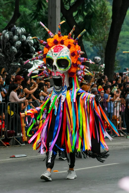 a skeleton with colorful feathers walking down a street