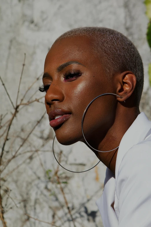 a woman with makeup on and ear piercings looking to her left