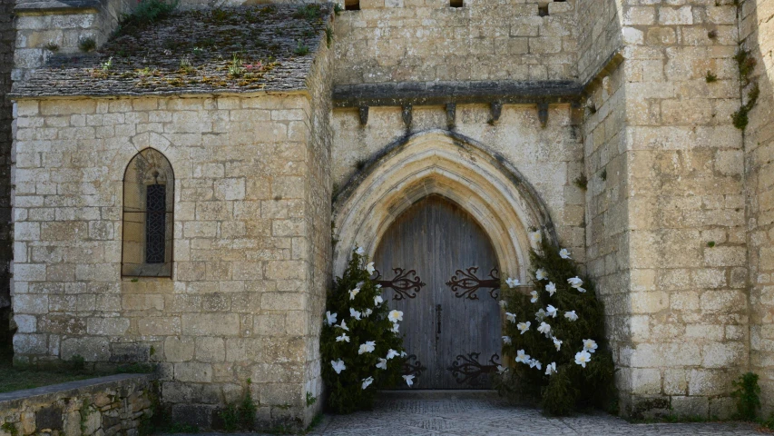 a stone building with arched doorways and flowers near it