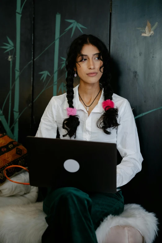 a person wearing a white shirt sits with a black laptop