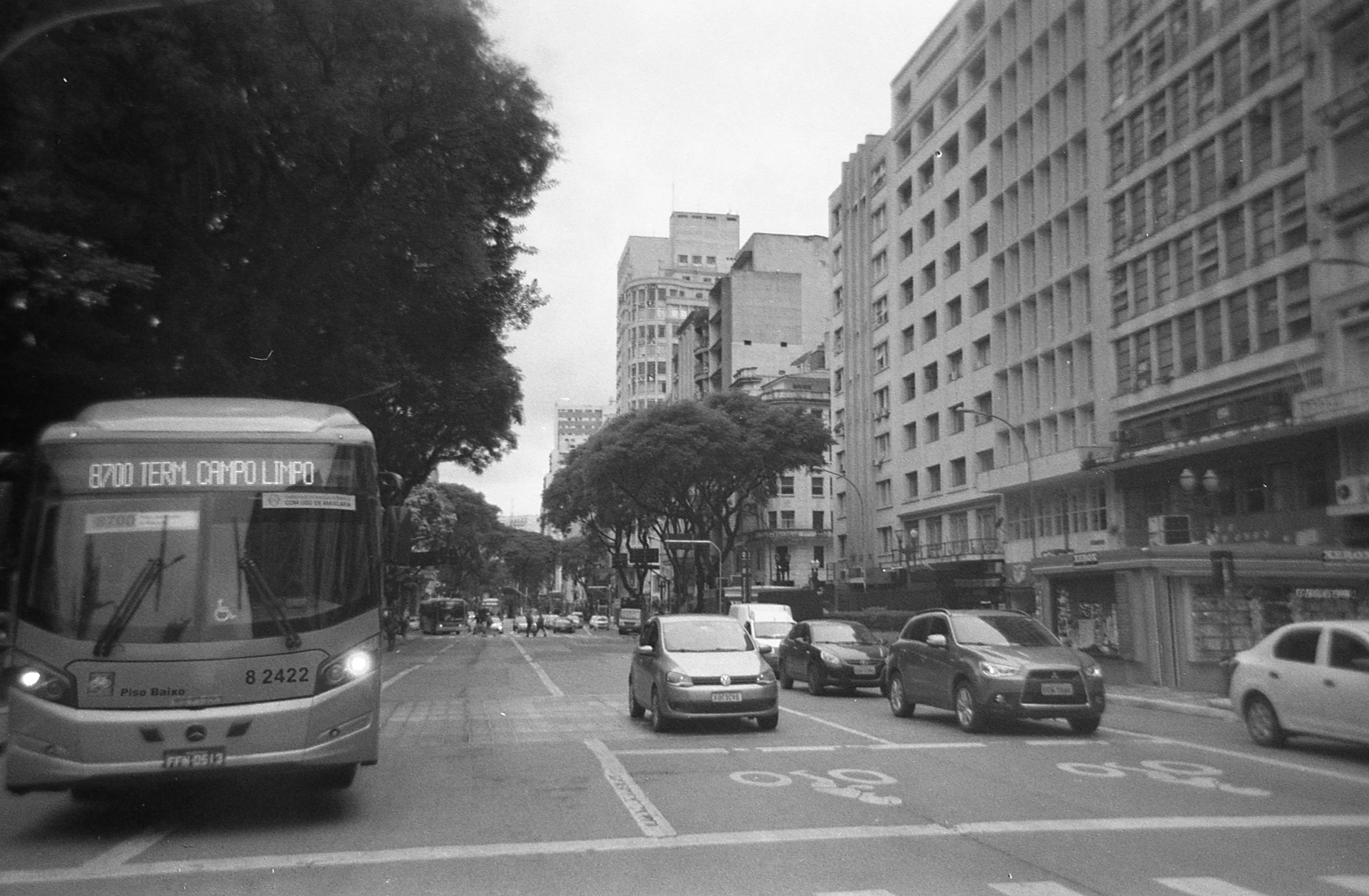 cars and buses drive along a city street