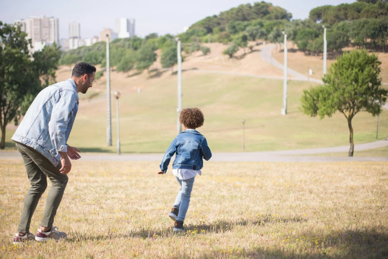 a father and his son standing in the grass in a park