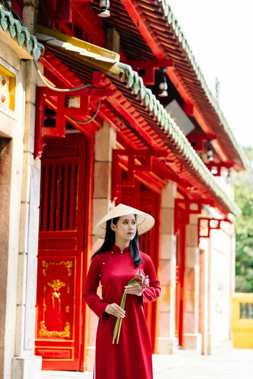 a woman in a long - sleeved red dress poses for a pograph while standing in front of an oriental structure