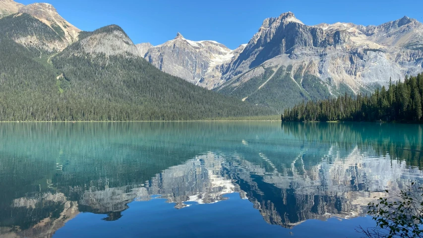 a view of mountains, trees and water that are in the foreground