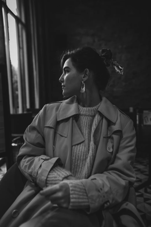 black and white po of a woman sitting next to a window